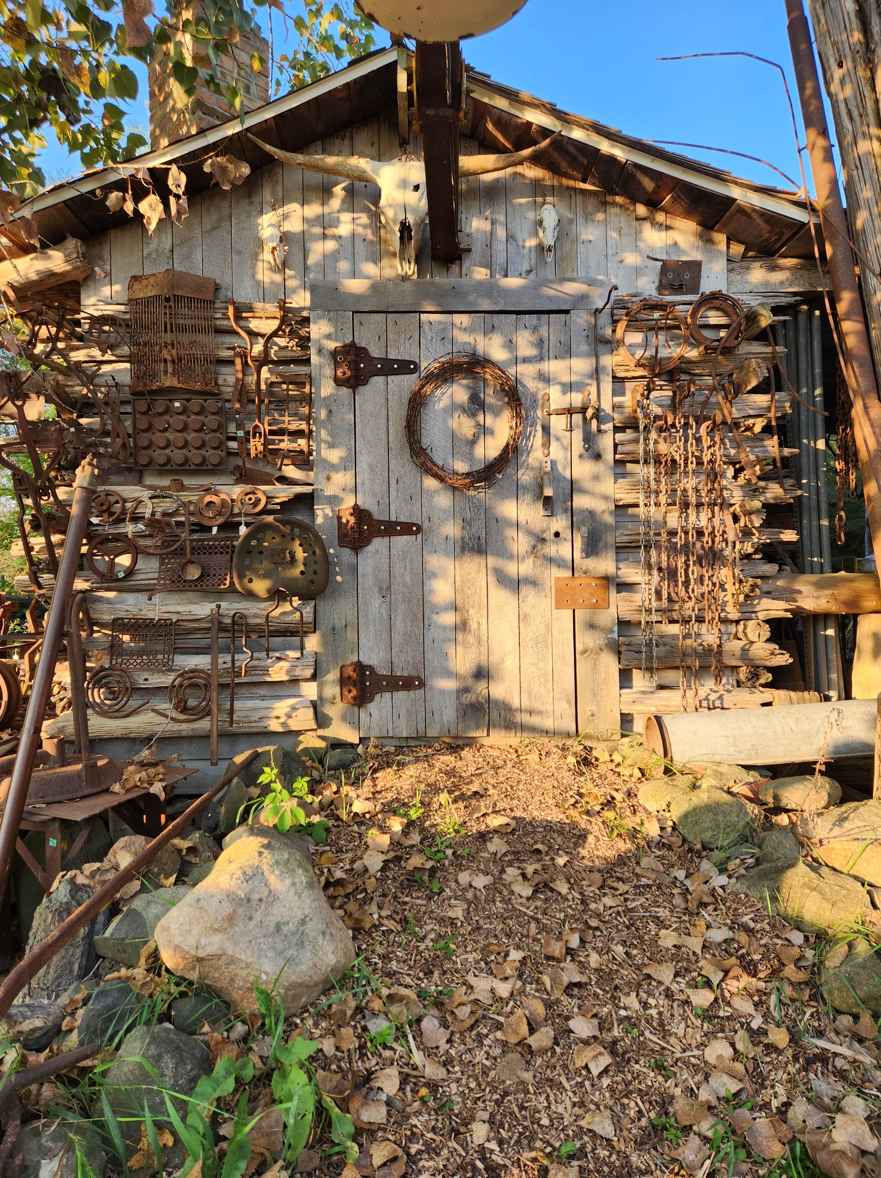 Small logcabin covered in differnt scrap metals known as the blacksmith shop